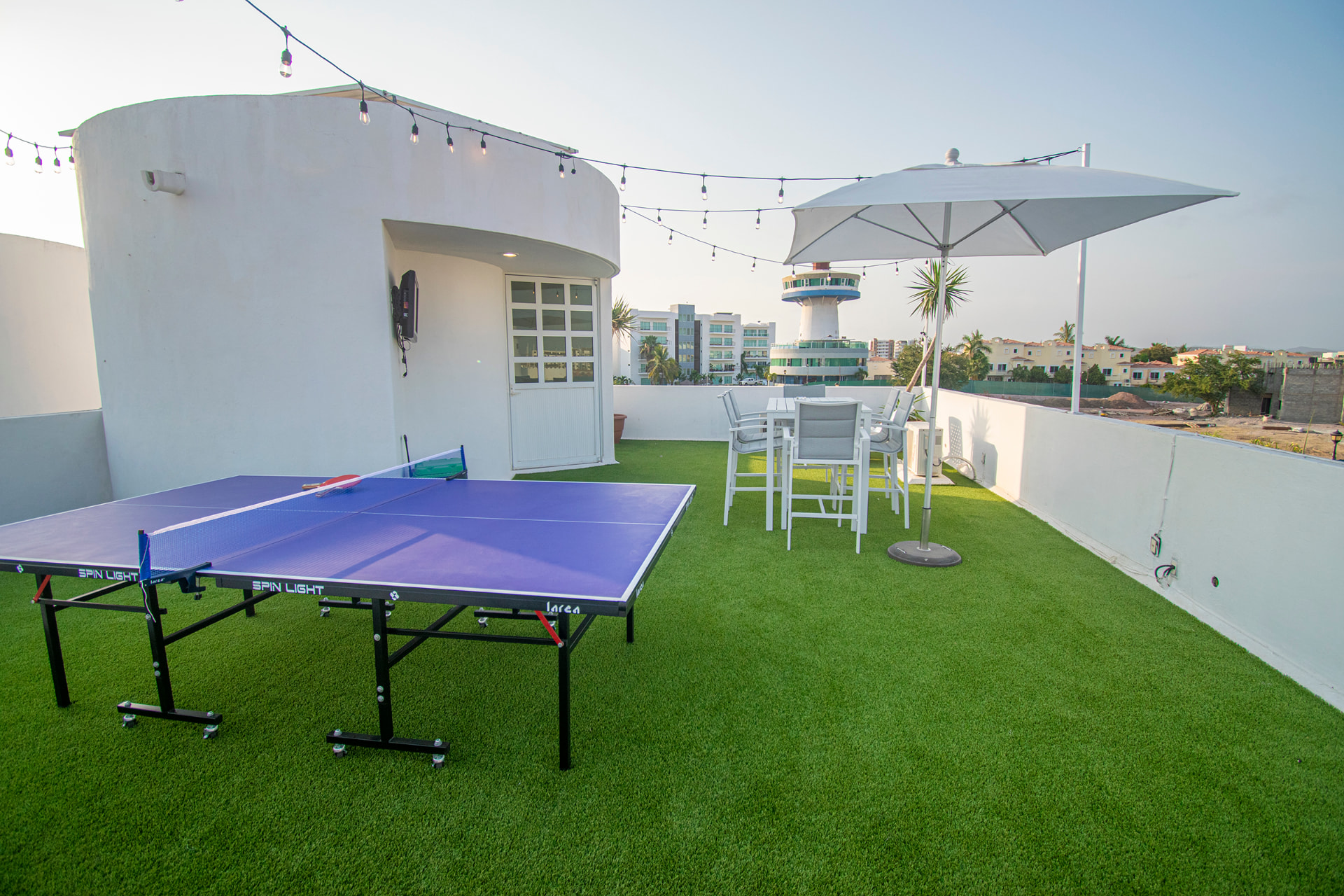Terraza superior con mesa de ping-pong, sombrilla y vista a la ciudad