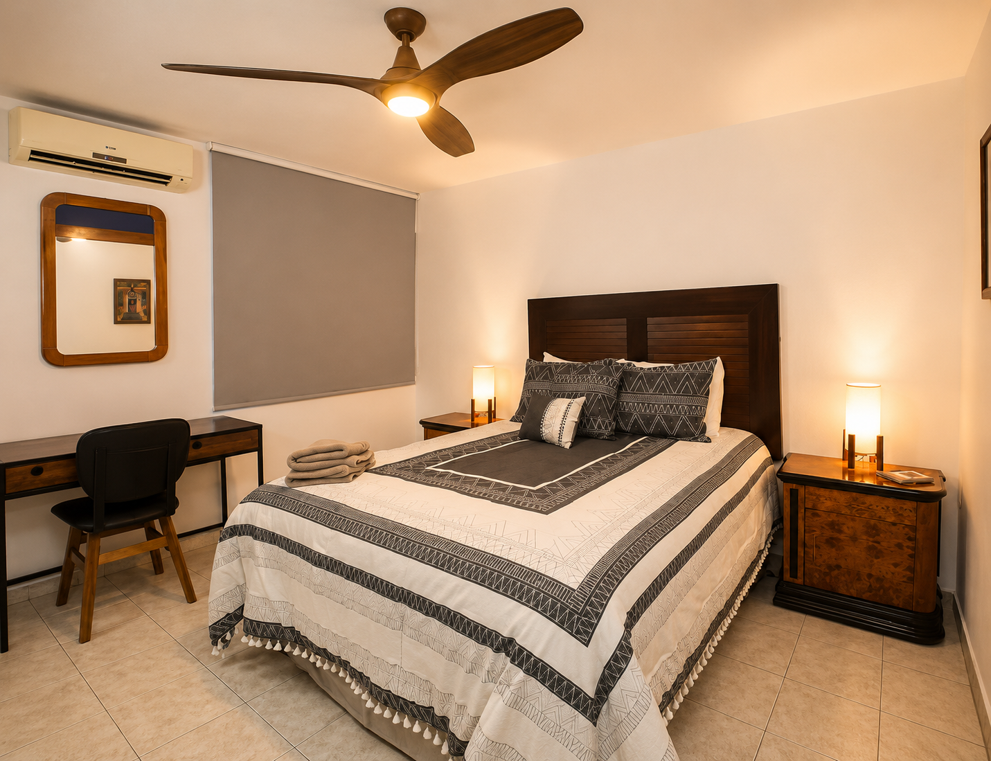 Recámara con cama matrimonial, aire acondicionado y área de trabajo con escritorio